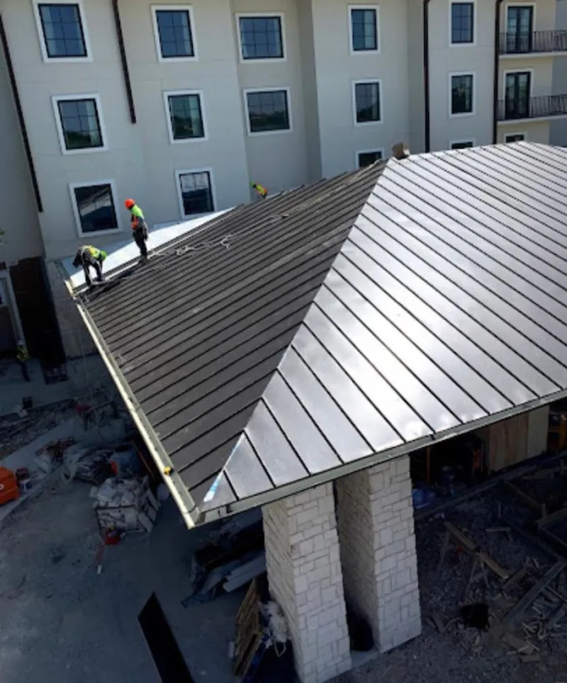 Crew installing standing seam metal roof panels on a commercial project in Rainbow City